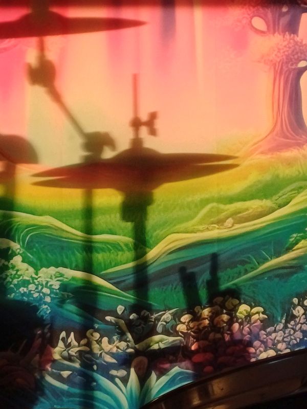 Schlagzeug-Silhouette vor buntem Regenbogen-Motiv